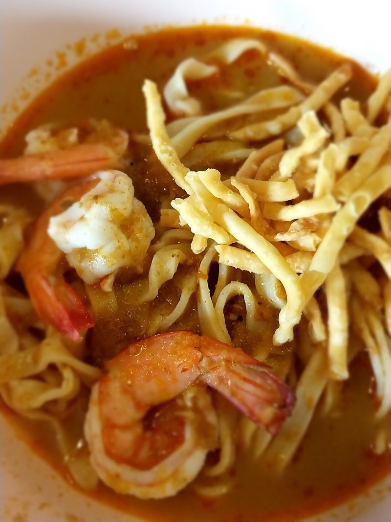 ข้าวซอยกุ้งในน้ำแกงสีส้มแดง เส้นกรอบวางด้านบน