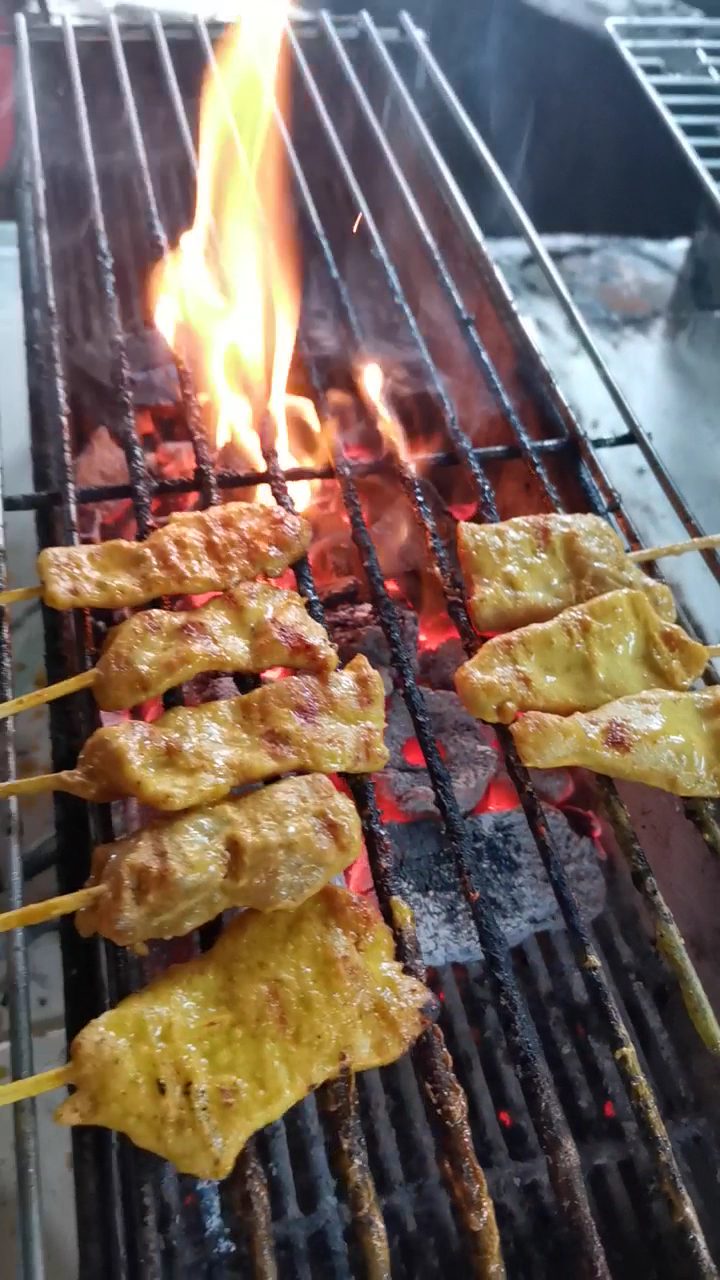 หมูสะเต๊ะเสียบไม้บนตะแกรงเตาถ่าน มีเปลวไฟลุกขึ้นมา