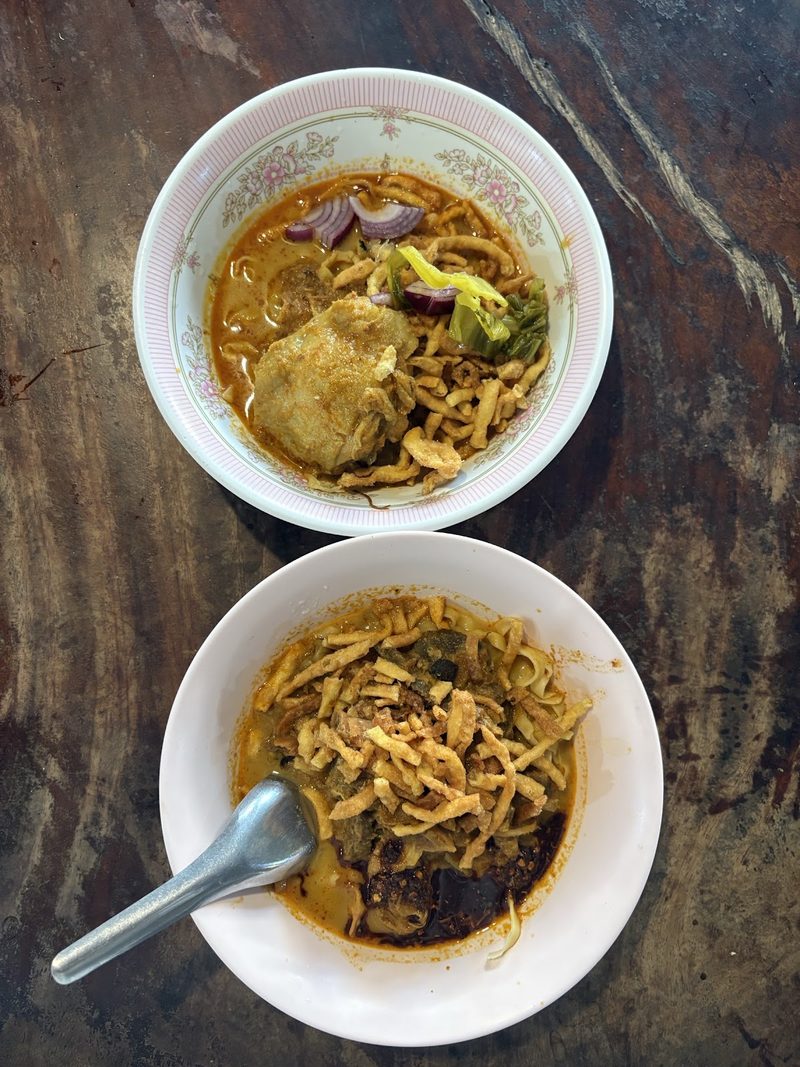 ข้าวซอยสองชามบนโต๊ะไม้สีเข้ม มองจากด้านบน